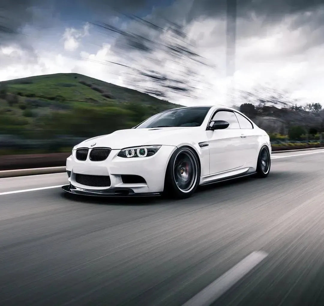 Front three-quarter rolling view of a white BMW E92 M3 fitted with AlpineX Dynamics MP style carbon fiber side skirts