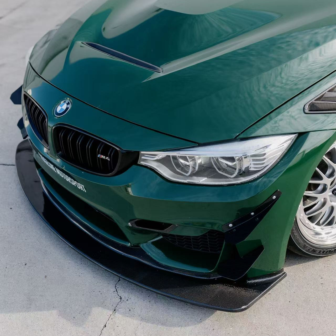 GT4+ carbon front lip and canards installed on a green BMW F82 M4