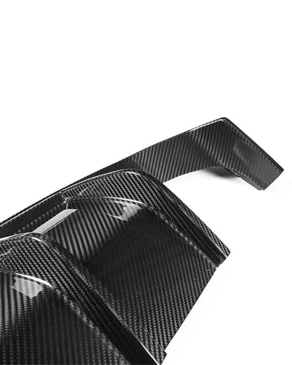 Close-up of the glossy carbon weave and sculpted fins on the AlpineX Dynamics V style three-piece rear diffuser for BMW F8X M3/M4, photographed against white