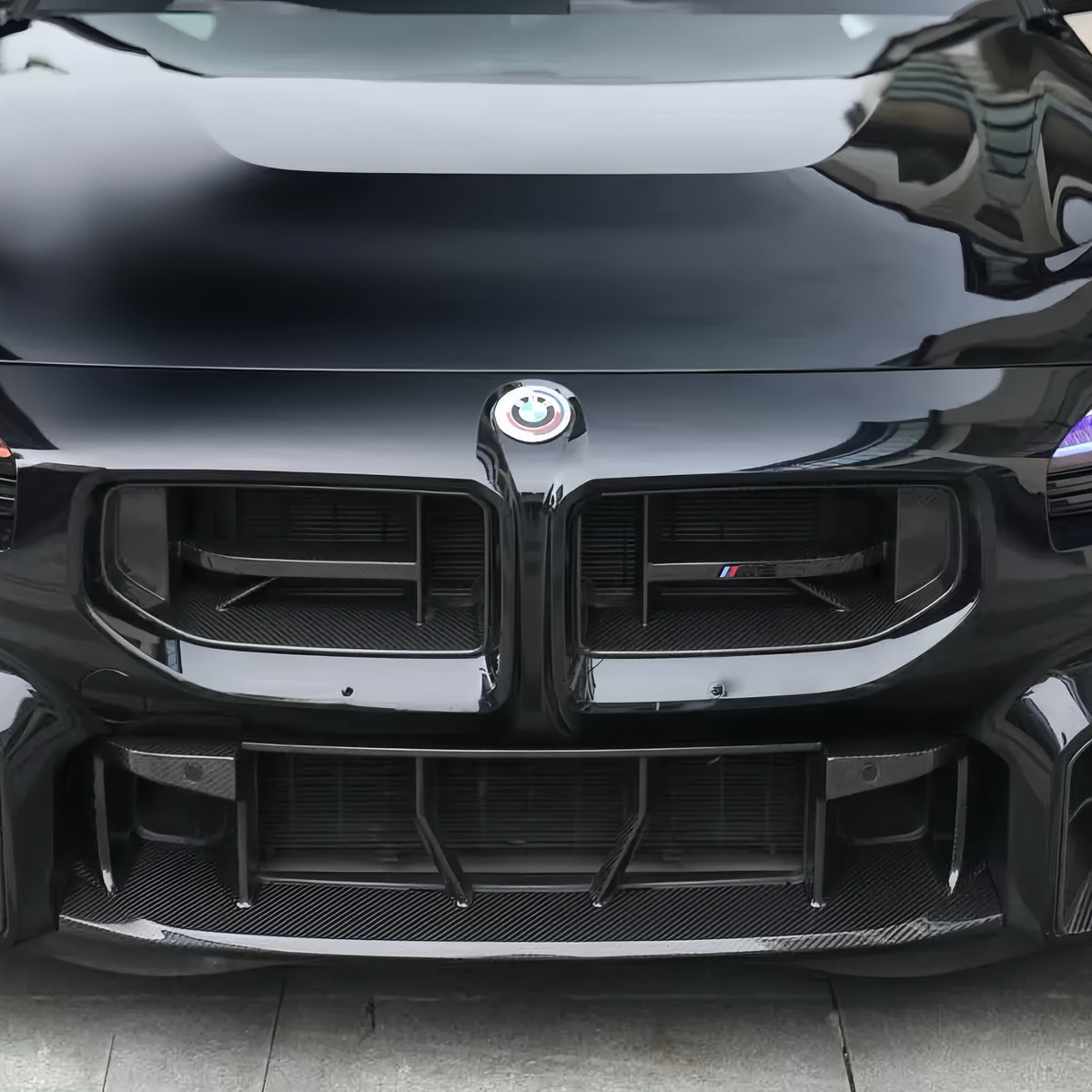 Front close-up of the AlpineX Dynamics CS style pre-preg dry carbon fiber grille installed on a black BMW G87 M2