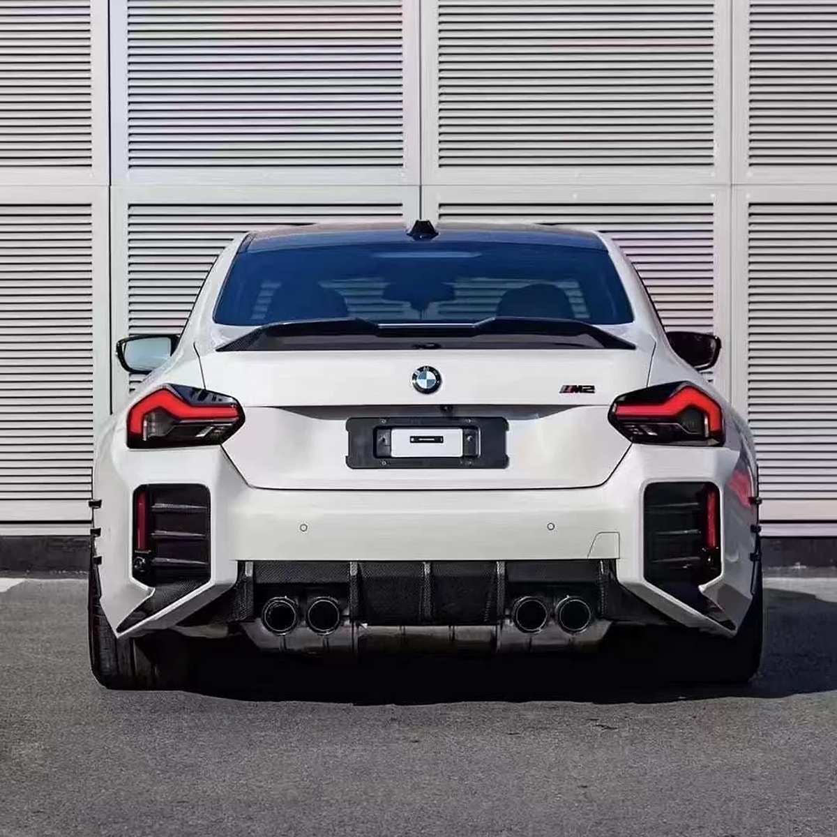 Rear view of a white BMW G87 M2 with the AlpineX Dynamics MP style pre-preg dry carbon fiber rear diffuser surrounding the quad exhaust tips
