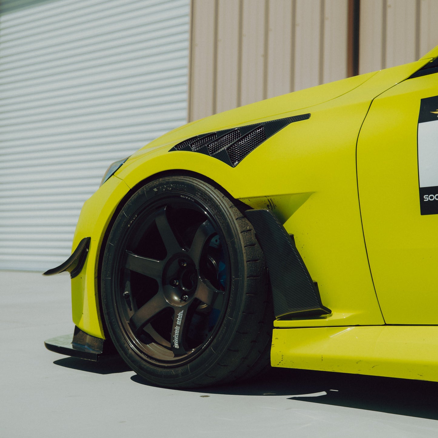 Side profile of a BMW G87 M2 carbon fiber canard positioned ahead of the front wheel