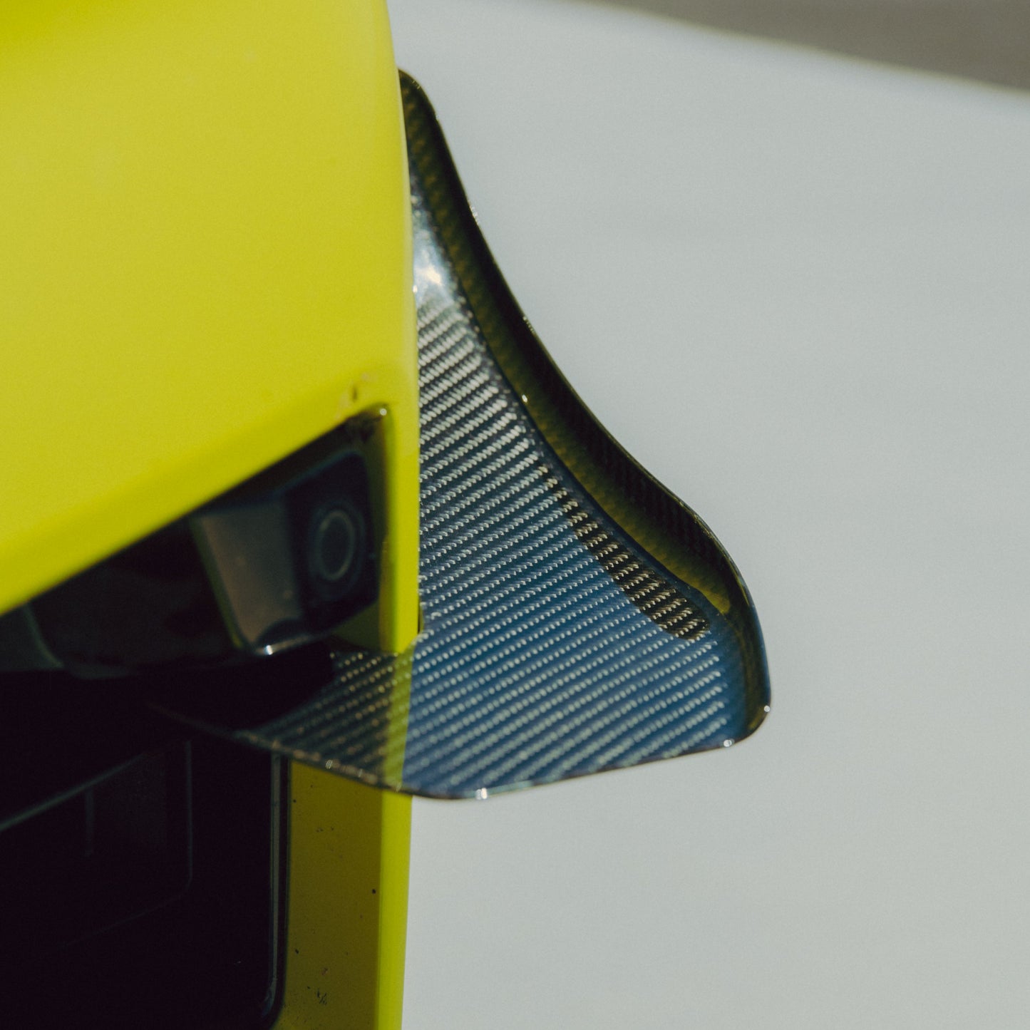 Close-up of the contoured carbon fiber canard mounted to the outer BMW G87 M2 front bumper