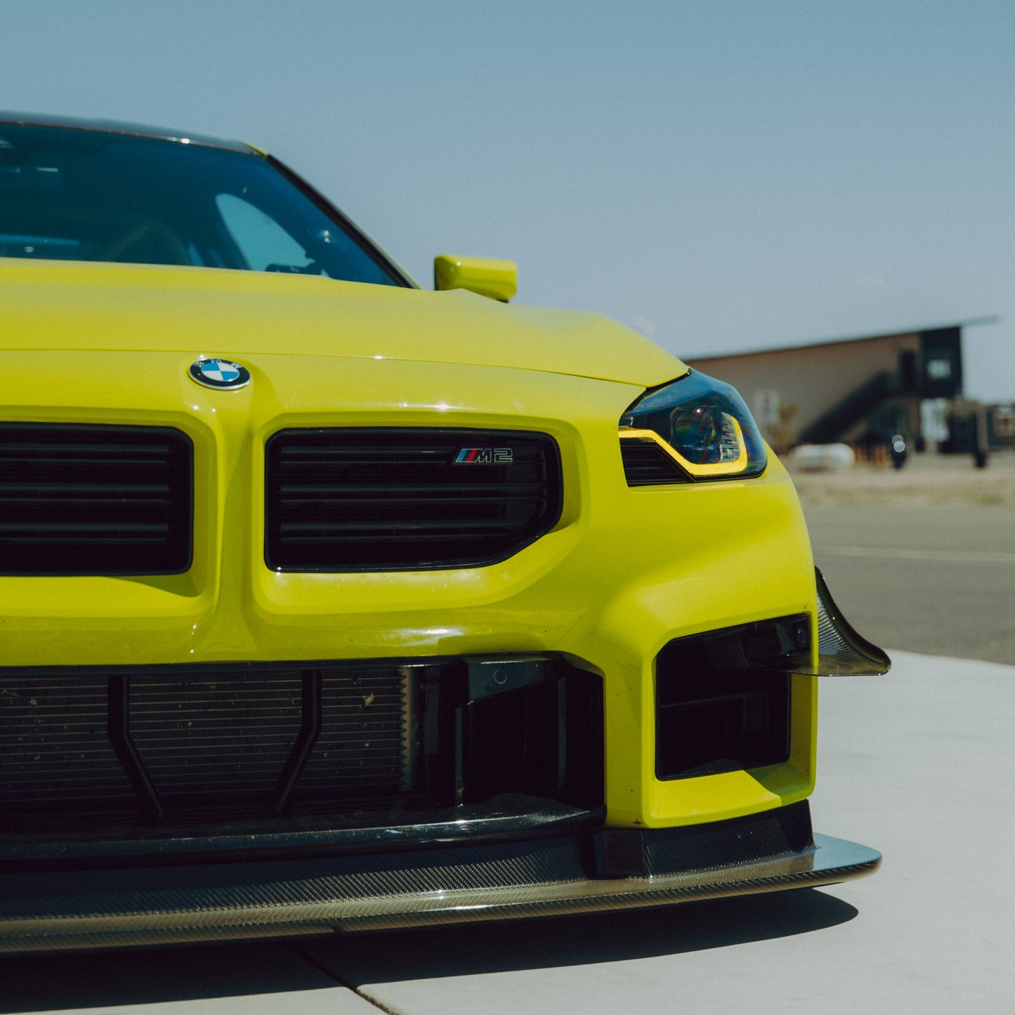 Front view of a yellow BMW G87 M2 with GT4+ carbon fiber canards and front splitter installed