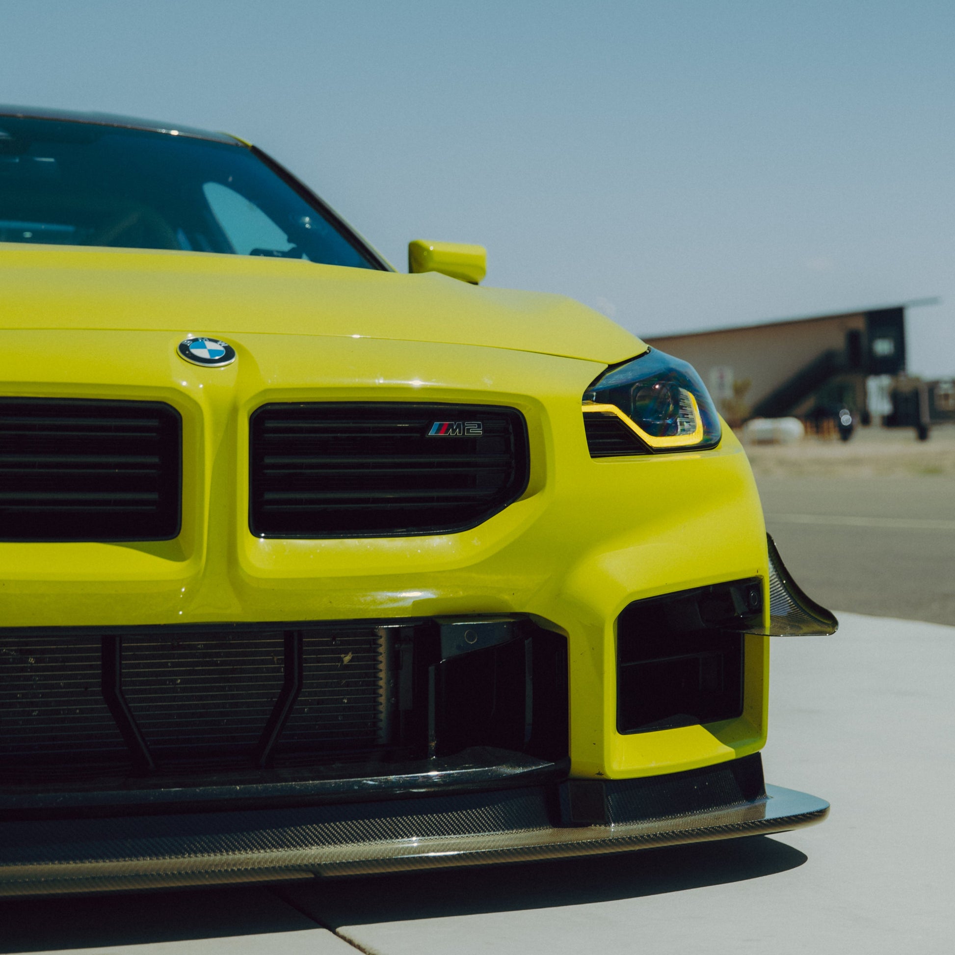 Front view of a yellow BMW G87 M2 with GT4+ carbon fiber canards and front splitter installed