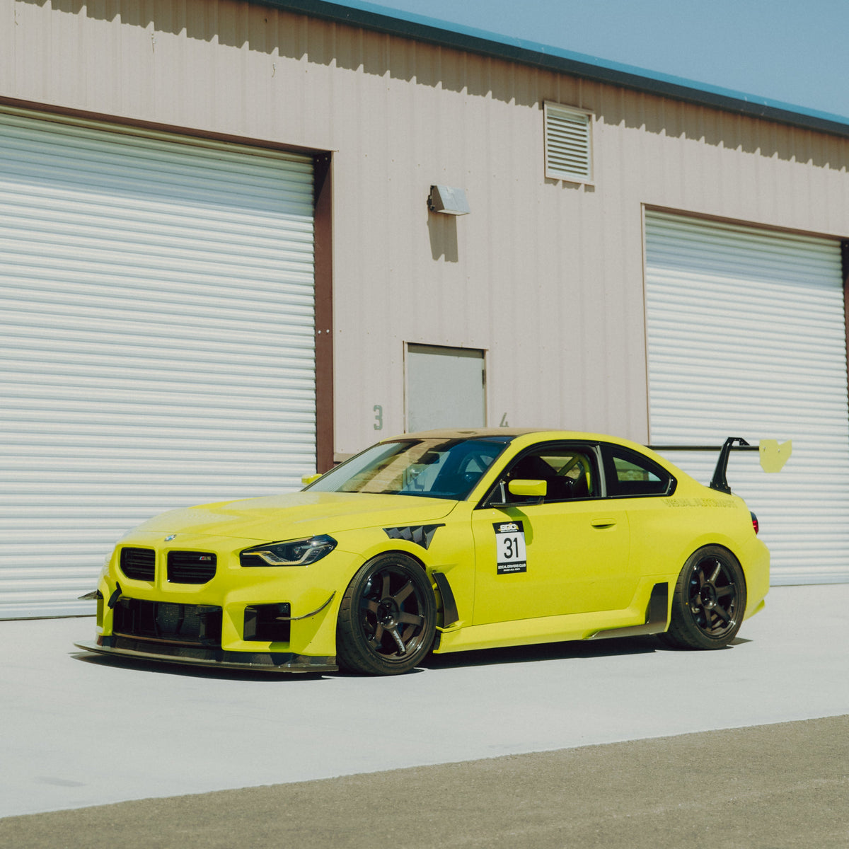 Yellow BMW G87 M2 fitted with GT4+ carbon fiber canards, front splitter and rear wing
