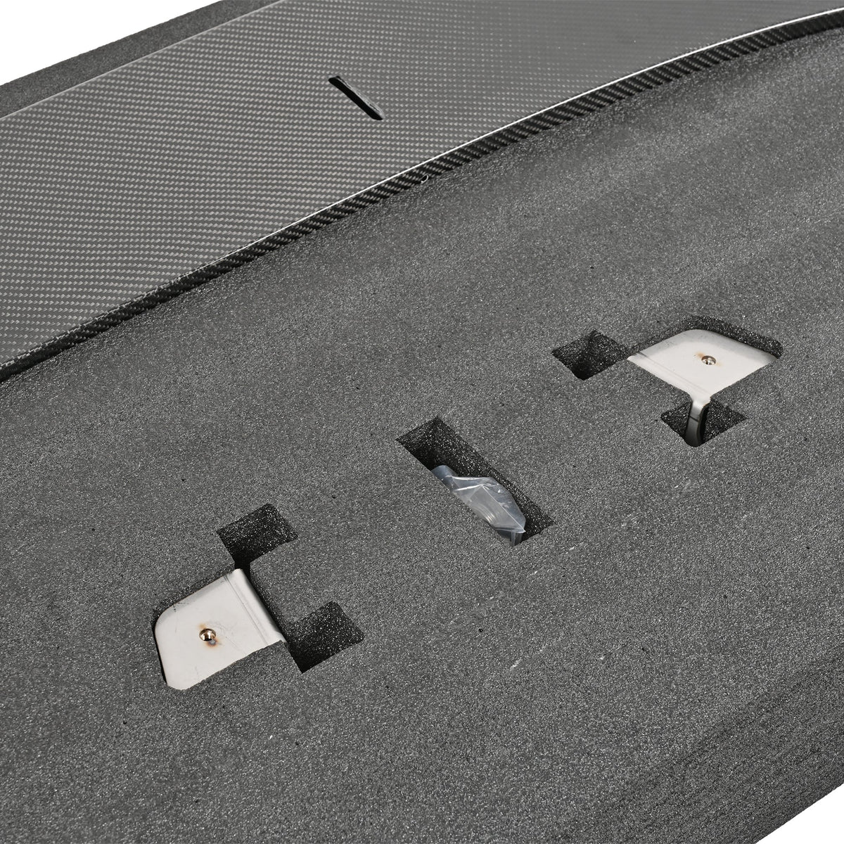 Close-up of the G87 M2 adjustable front splitter mounting hardware and carbon fiber adjustment slot in protective packaging