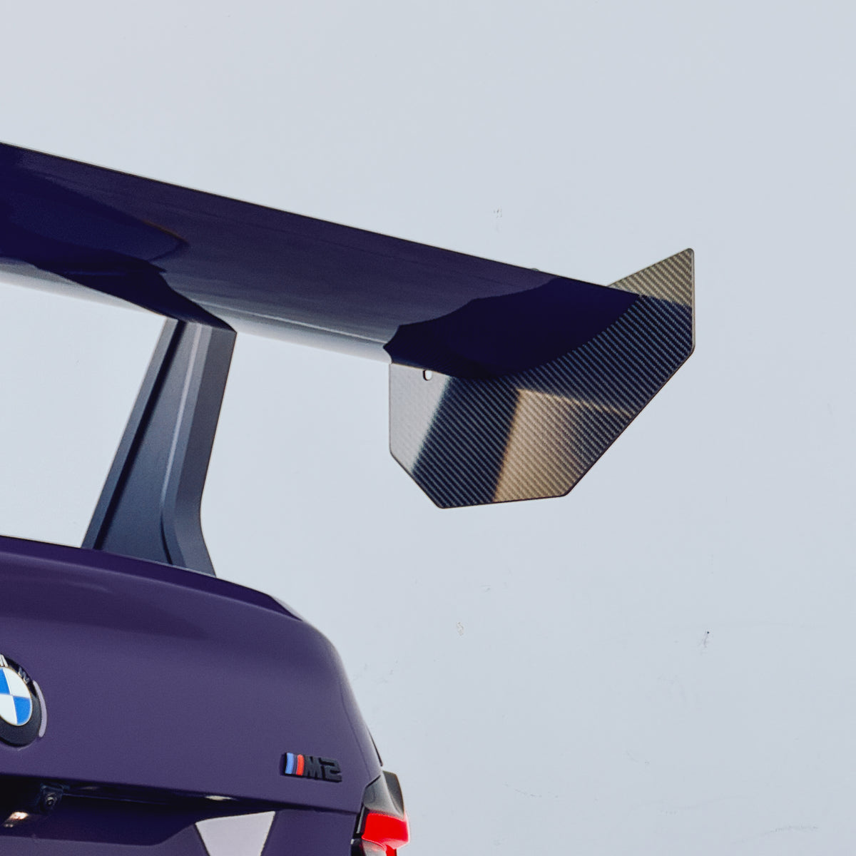 Installed detail of the carbon fiber endplate and mainplane on an Ultraviolet BMW G87 M2 GT4+ rear wing