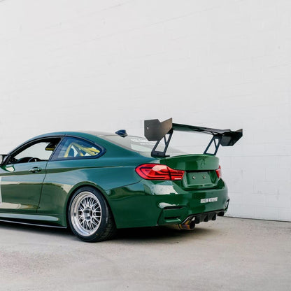 Rear three-quarter view of a green BMW F82 M4 with the GT4+ 1600 mm chassis-mounted rear wing installed