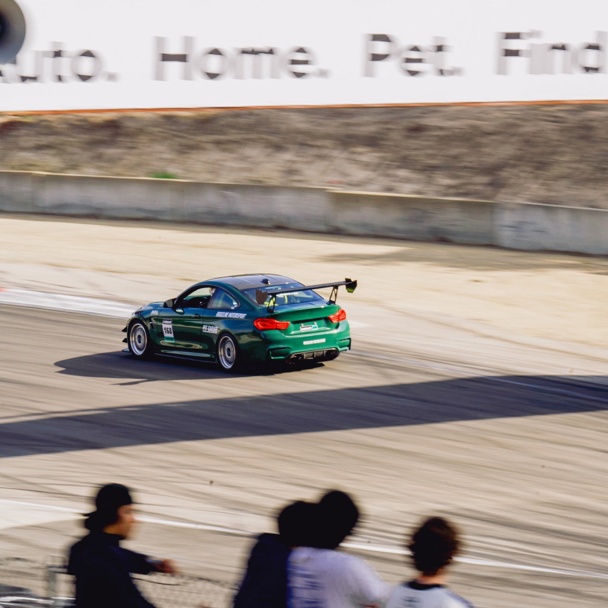 Green BMW F82 M4 with GT4+ 1600 mm chassis-mounted rear wing driving at WeatherTech Raceway Laguna Seca