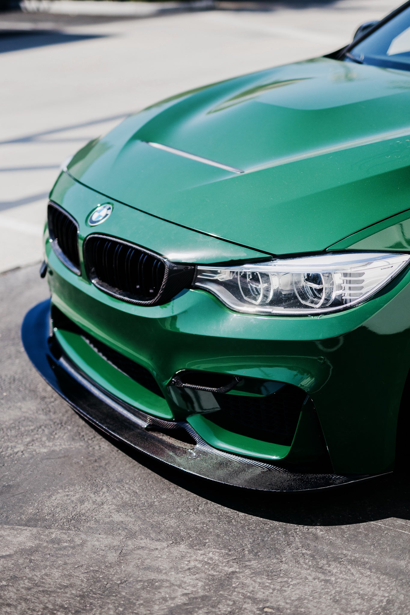 Front three-quarter view of a green BMW F82 M4 with the GT4 V2 carbon fiber splitter