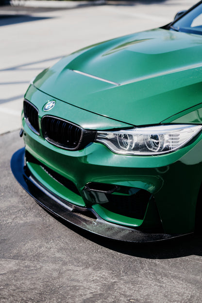 Front three-quarter view of a green BMW F82 M4 with the GT4 V2 carbon fiber splitter