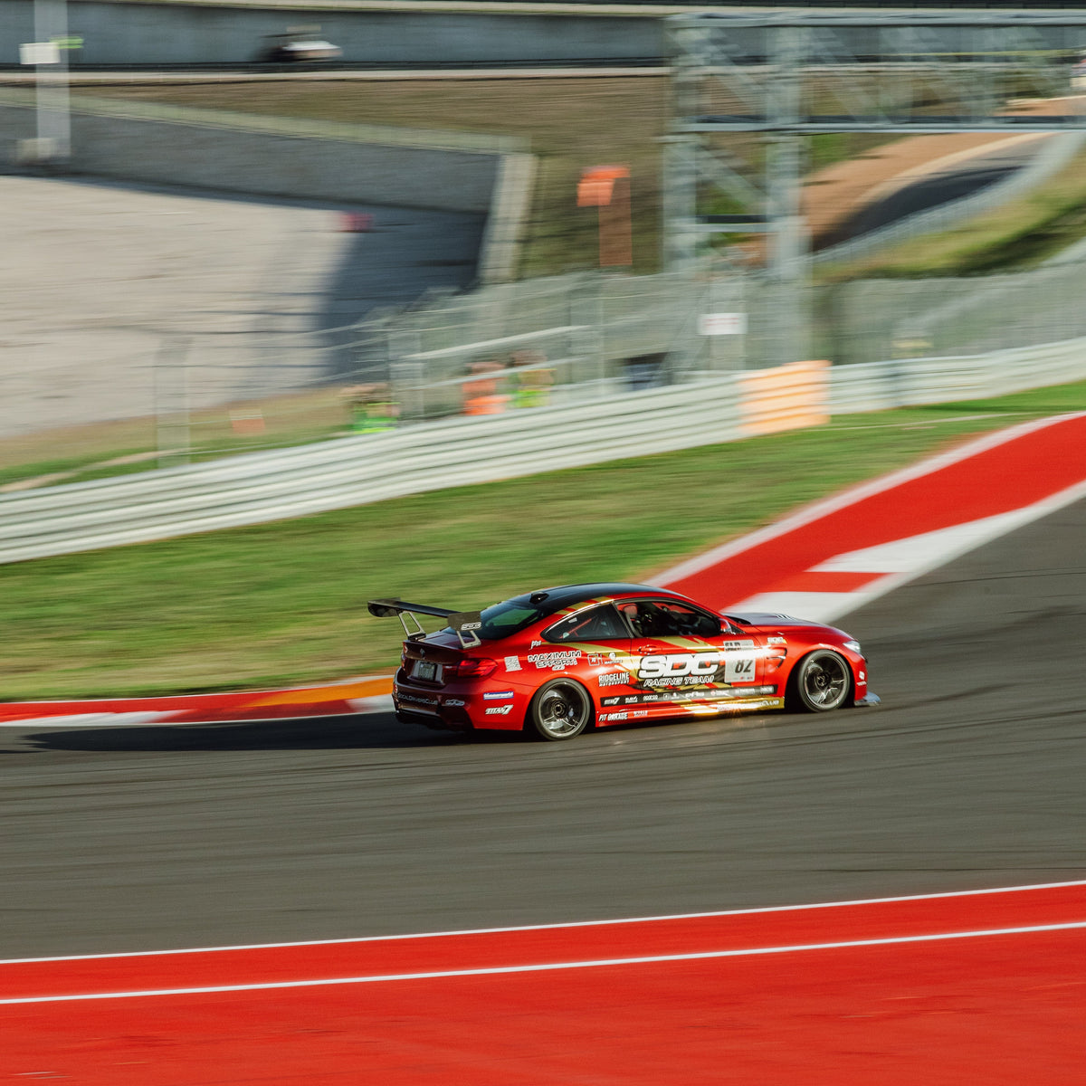 Red BMW F80 M3 with GT4+ 1600 mm chassis-mounted rear wing driving on track