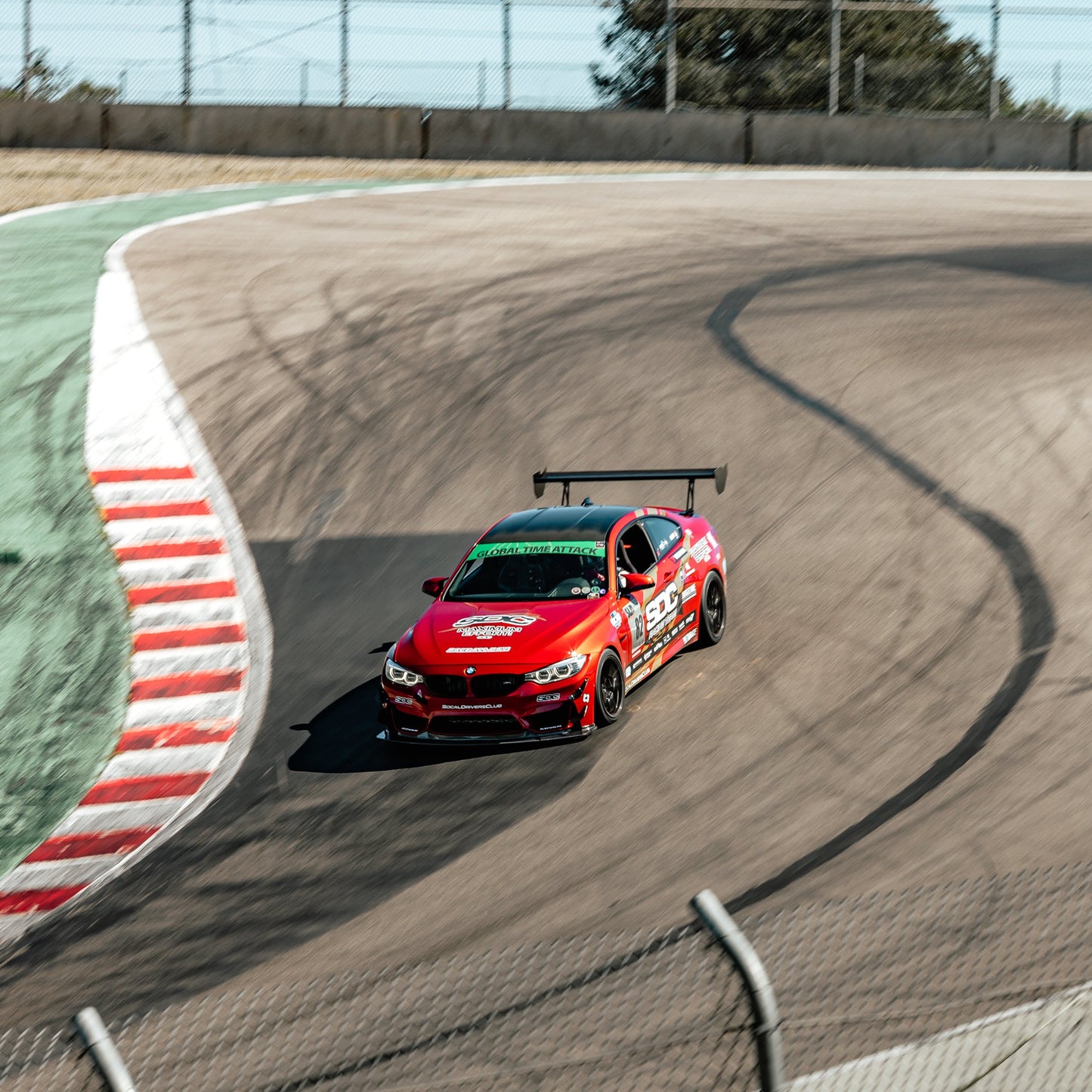Red BMW F80 M3 with GT4+ front splitter and rear wing driving on track