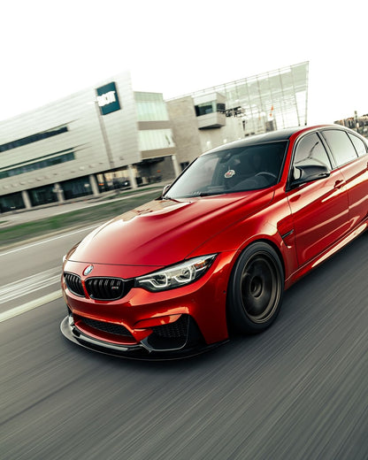 Red BMW F80 M3 with GT4 V1 carbon fiber front splitter in a front three-quarter rolling view