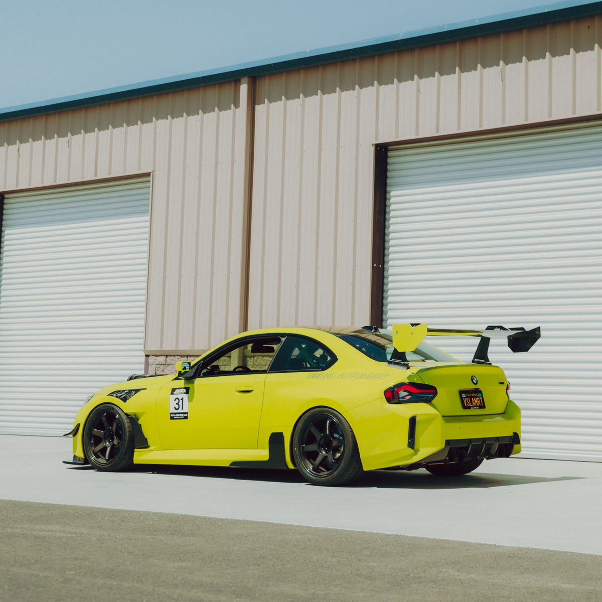Rear three-quarter view of a Sao Paulo Yellow BMW G87 M2 with the GT4+ swan-neck rear wing
