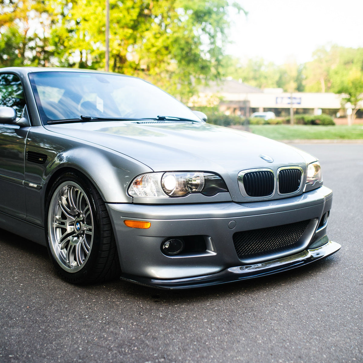 Silver BMW E46 M3 with carbon fiber GT4 front lip from front three-quarter angle