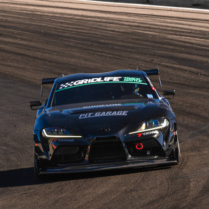 Front track view of a black Toyota GR Supra race car fitted with the RM Engineering GT4+ front splitter beneath the bumper