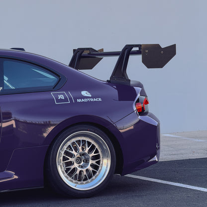 Side view of an Ultraviolet BMW G87 M2 with the GT4+ carbon fiber swan-neck rear wing installed