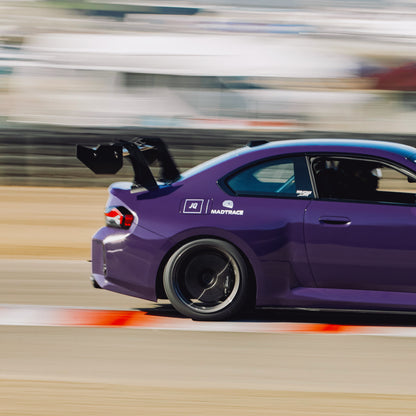 Track-side view of an Ultraviolet BMW G87 M2 with the GT4+ carbon fiber swan-neck wing
