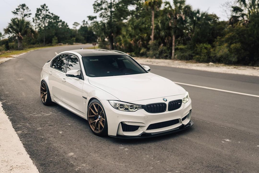 White BMW F82 M4 fitted with GT4 V1 carbon fiber front splitter on the road