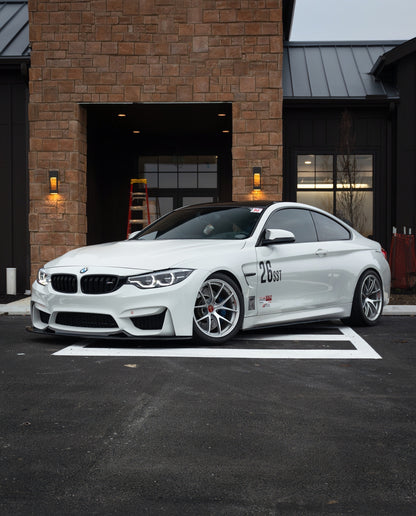 White BMW F82 M4 with GT4 V1 carbon fiber front splitter in a front-side view